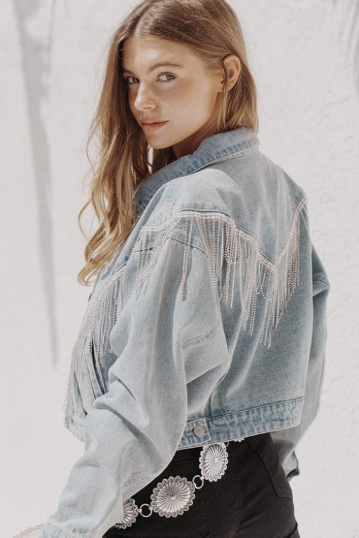 a young woman wearing a denim jacket with rhinestone fringe
